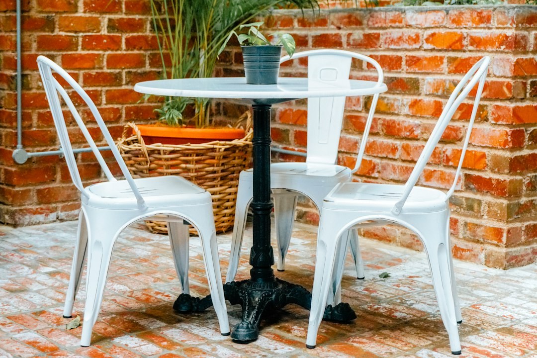 Row of white aluminum armless chairs on a paved outdoor floor
