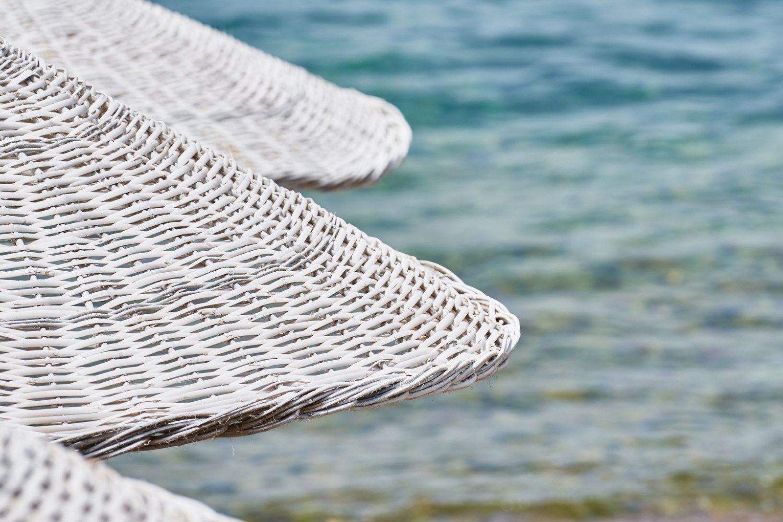 Close-up of white synthetic wicker weave on an outdoor seating frame