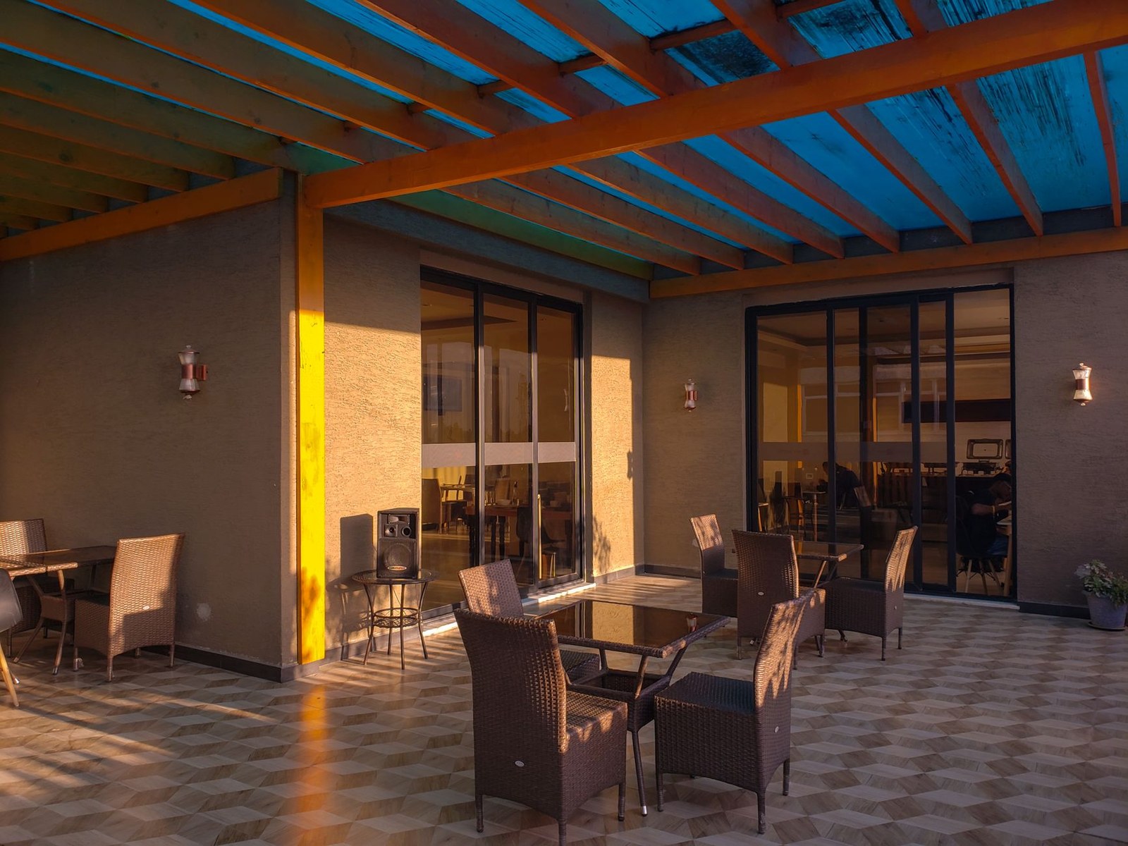 Sunlit restaurant patio with wicker lounge seating in daily commercial service