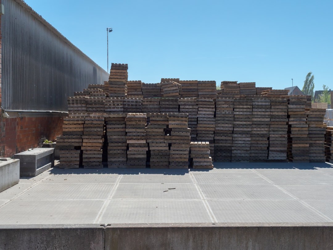 Caisses et palettes d'export en bois empilées sur une aire de chargement devant un entrepôt, avant expédition