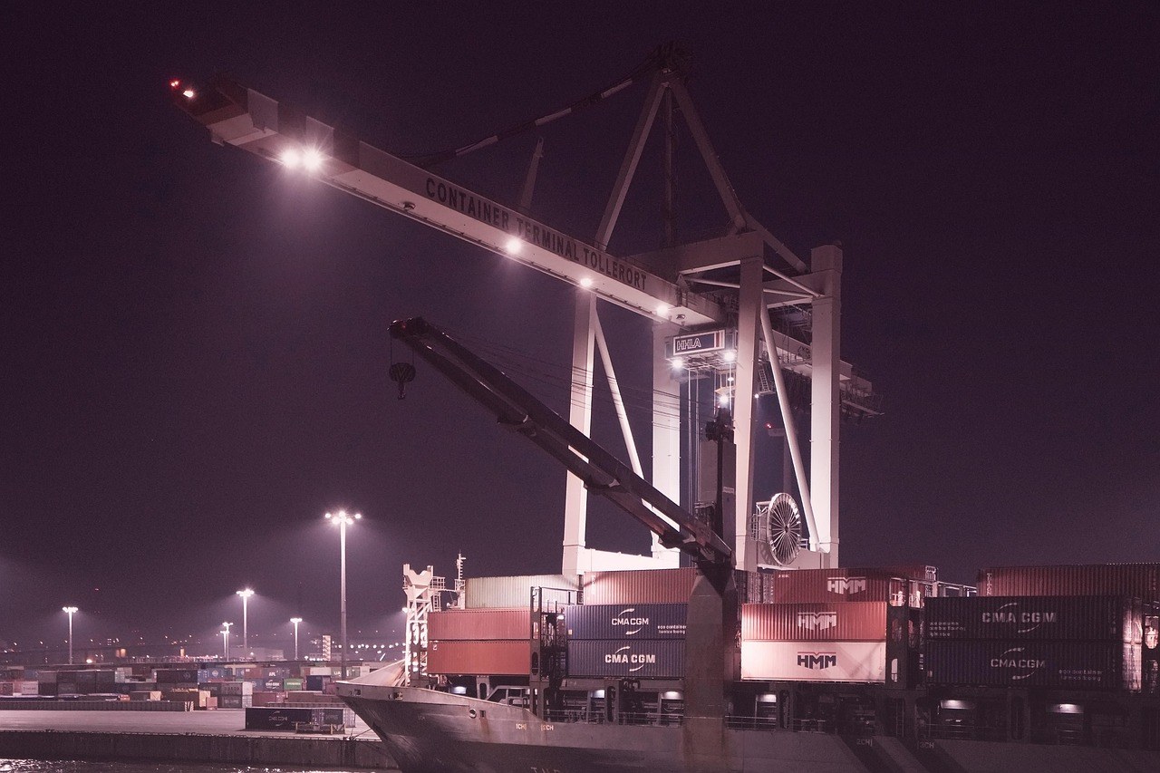Grúa de muelle y buque portacontenedores en un puerto de exportación durante la noche