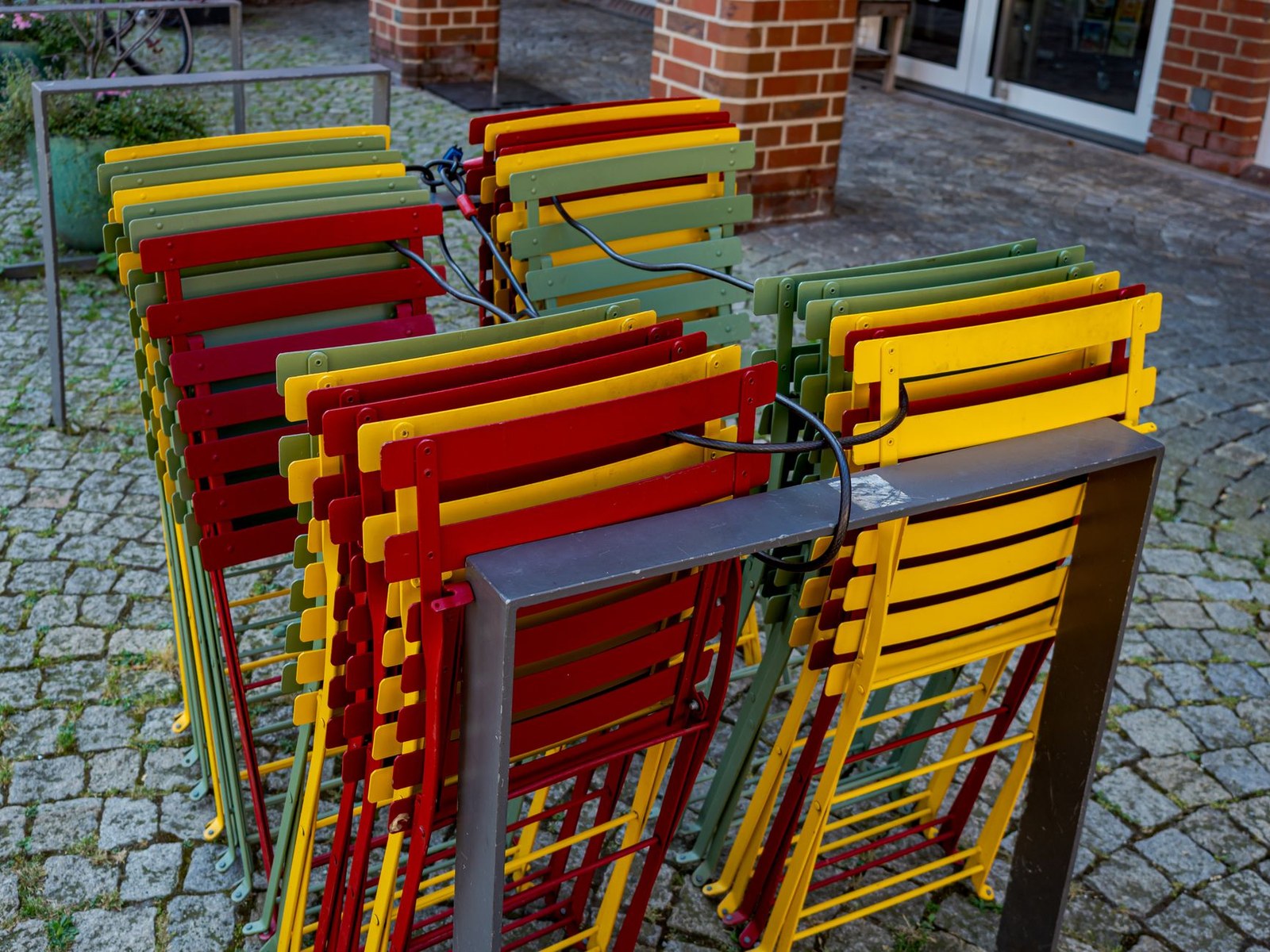 Sillas apilables de terraza con estructura metálica pintada apiladas en torre, detalle de apilado para hostelería