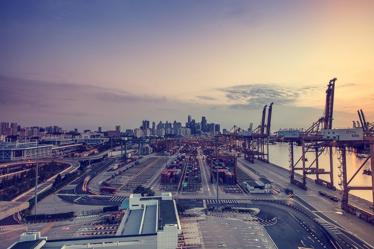 Puerto de contenedores con grúas de muelle y pilas de contenedores al amanecer, exportación de mobiliario de terraza desde China